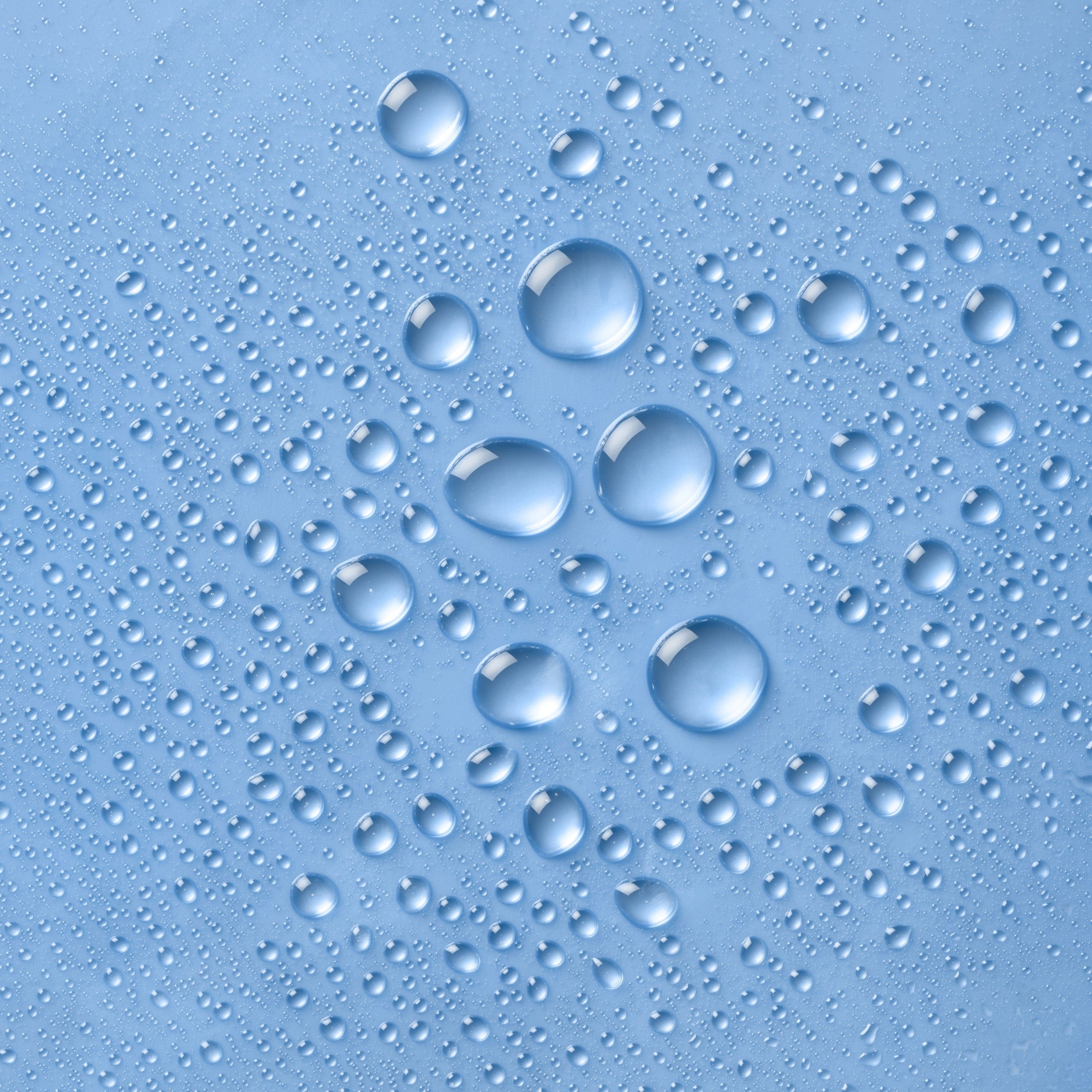 Close-up of multiple water droplets of varying sizes on a blue background, showcasing hydration and moisture concept.