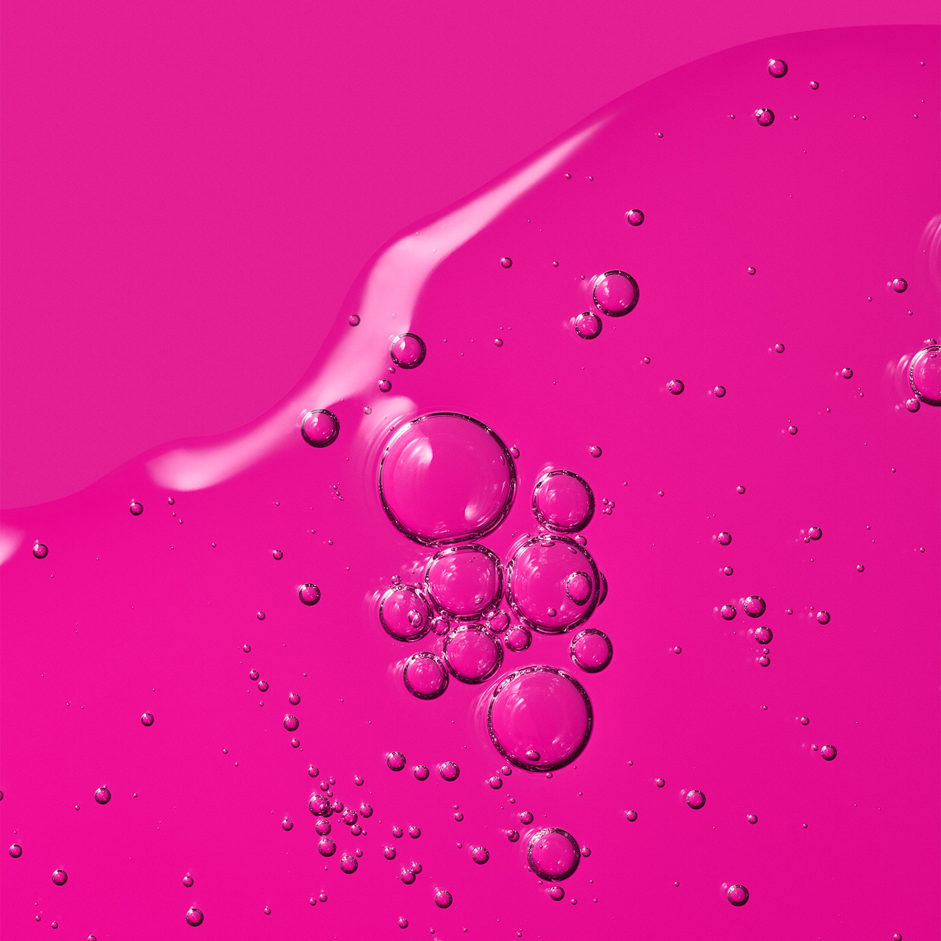 Transparent liquid with bubbles against a pink background.