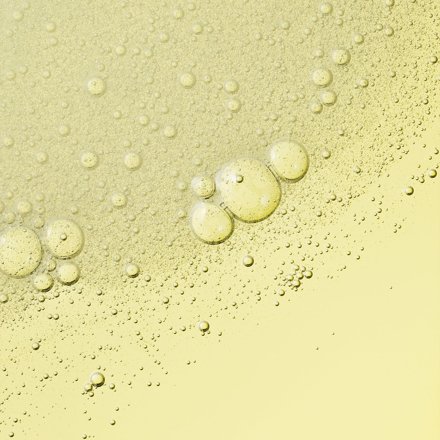 A transparent liquid with excessive bubbles on a yellow surface.