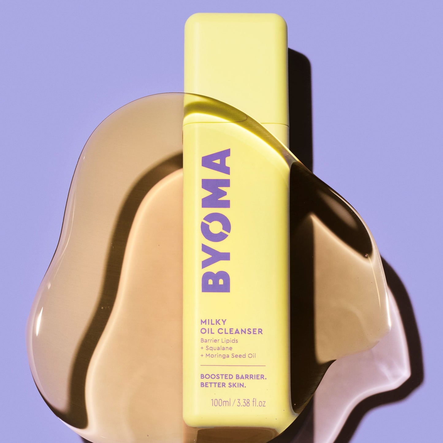 An amber coloured liquid over the BYOMA MILKY OIL CLEANSER in a blue background.