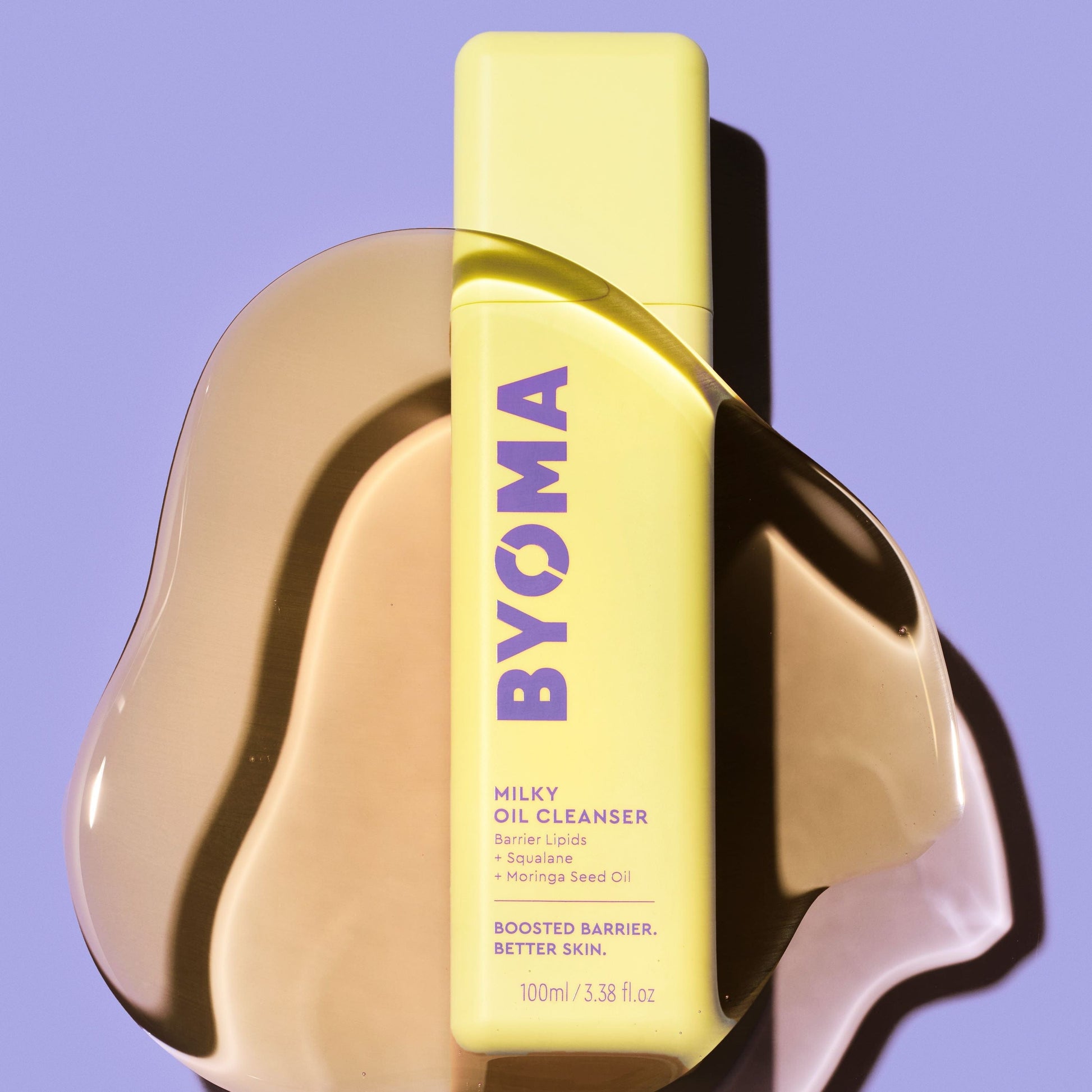An amber coloured liquid over the BYOMA MILKY OIL CLEANSER in a blue background.
