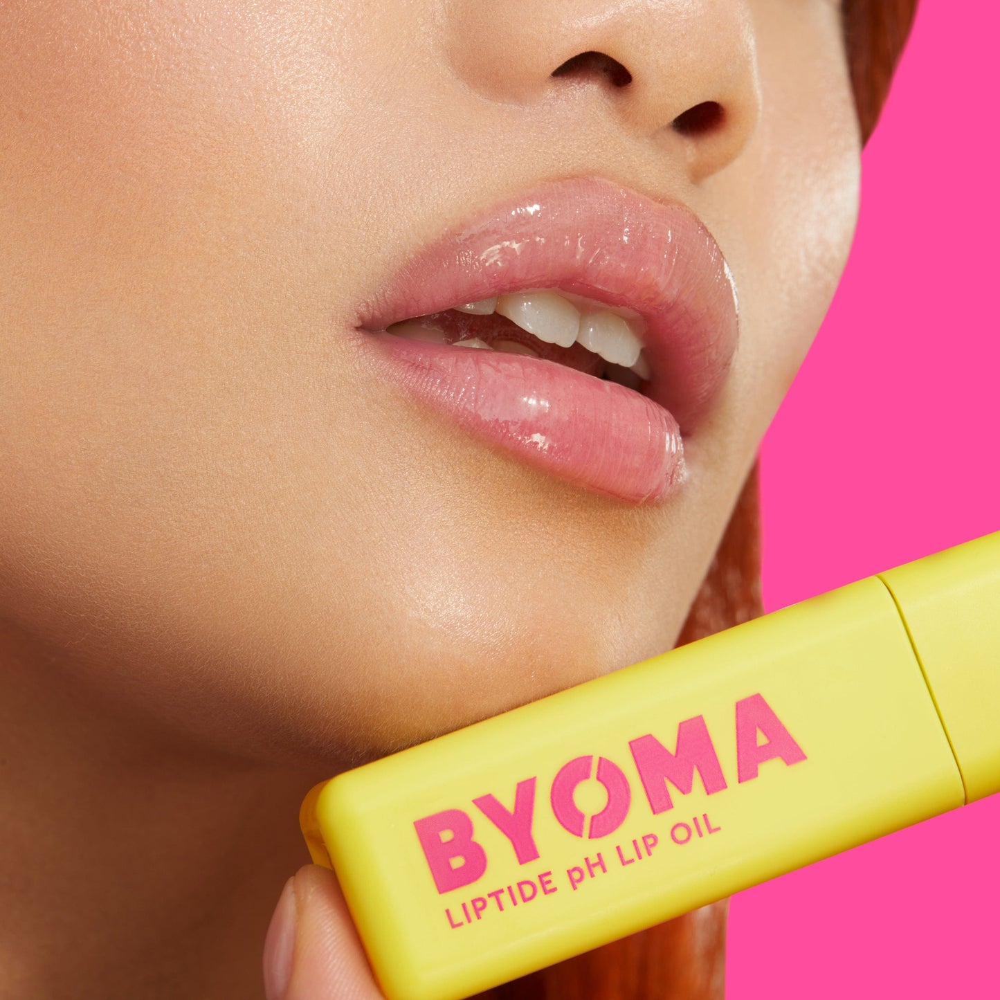 Closeup of a girl holding the BYOMA LIPTIDE pH LIP OIL against her lips.
