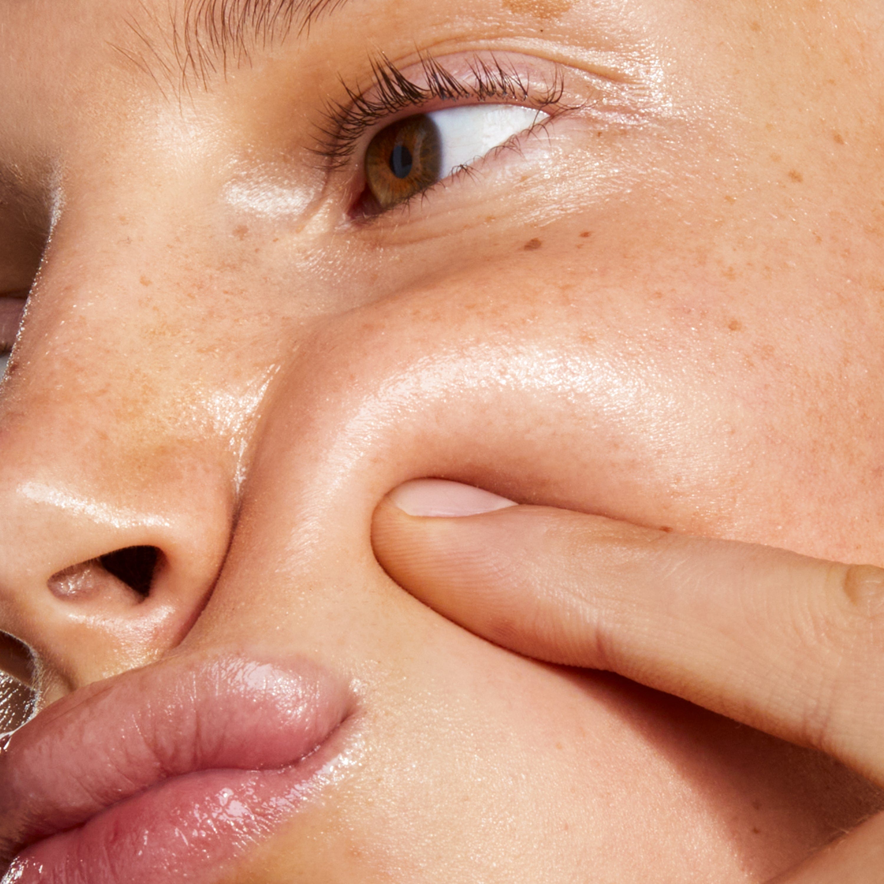 Closeup of a side face of a girl pressing her cheek with a finger.
