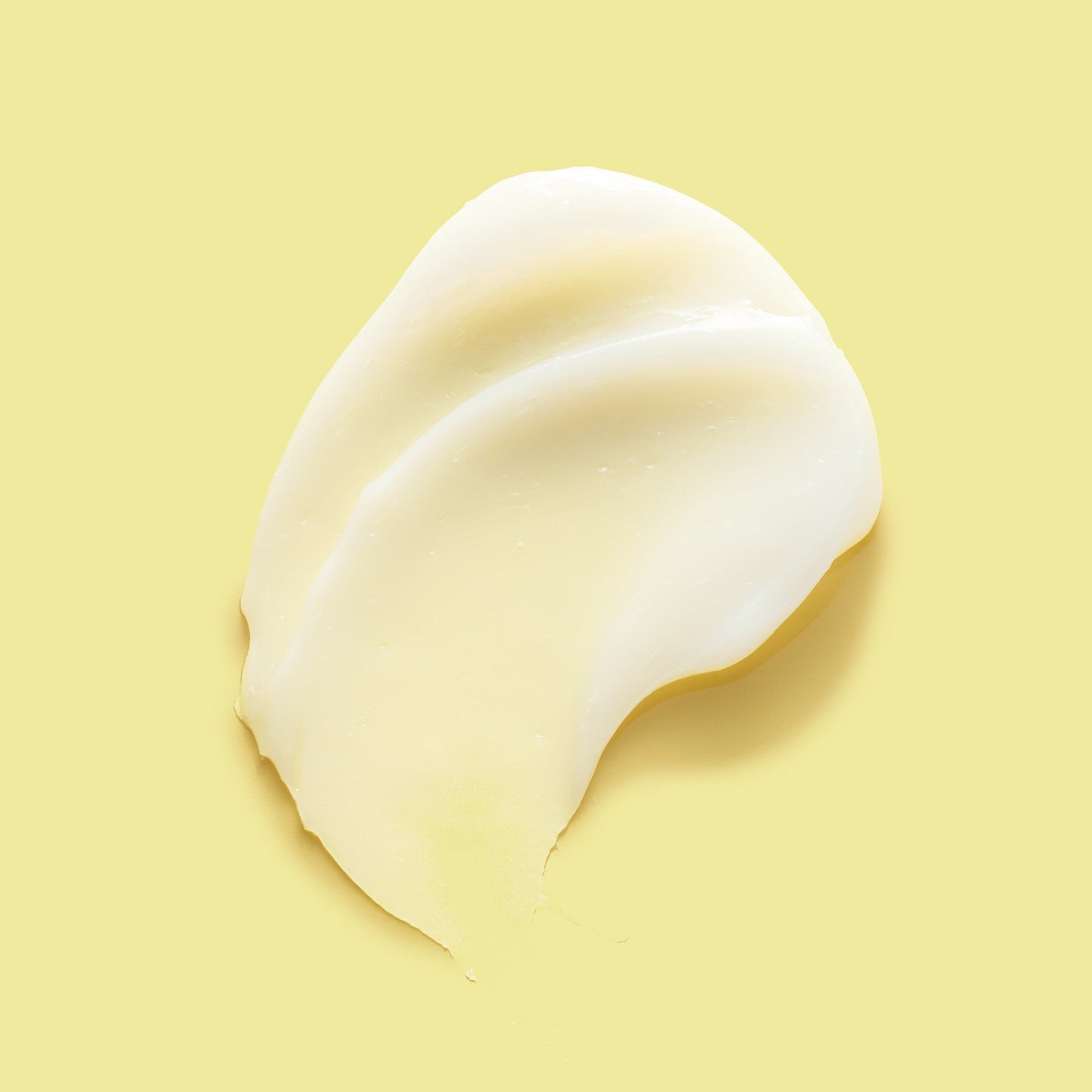 Thick white skincare product against a yellow background.