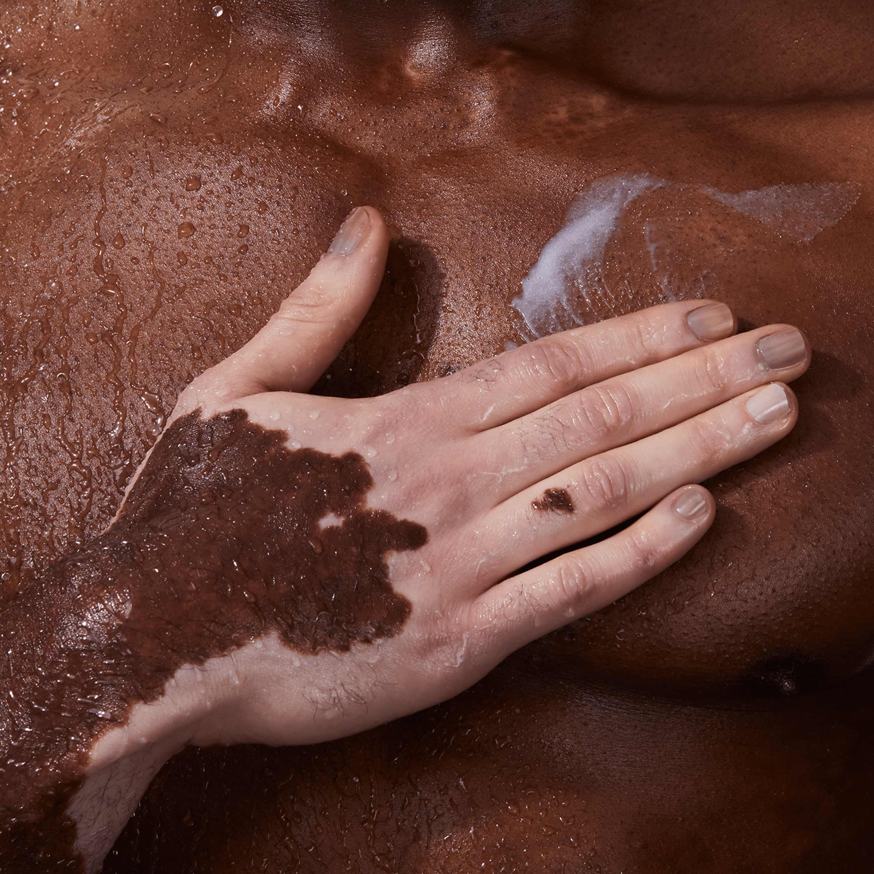 A hand applying product on a brown skin.