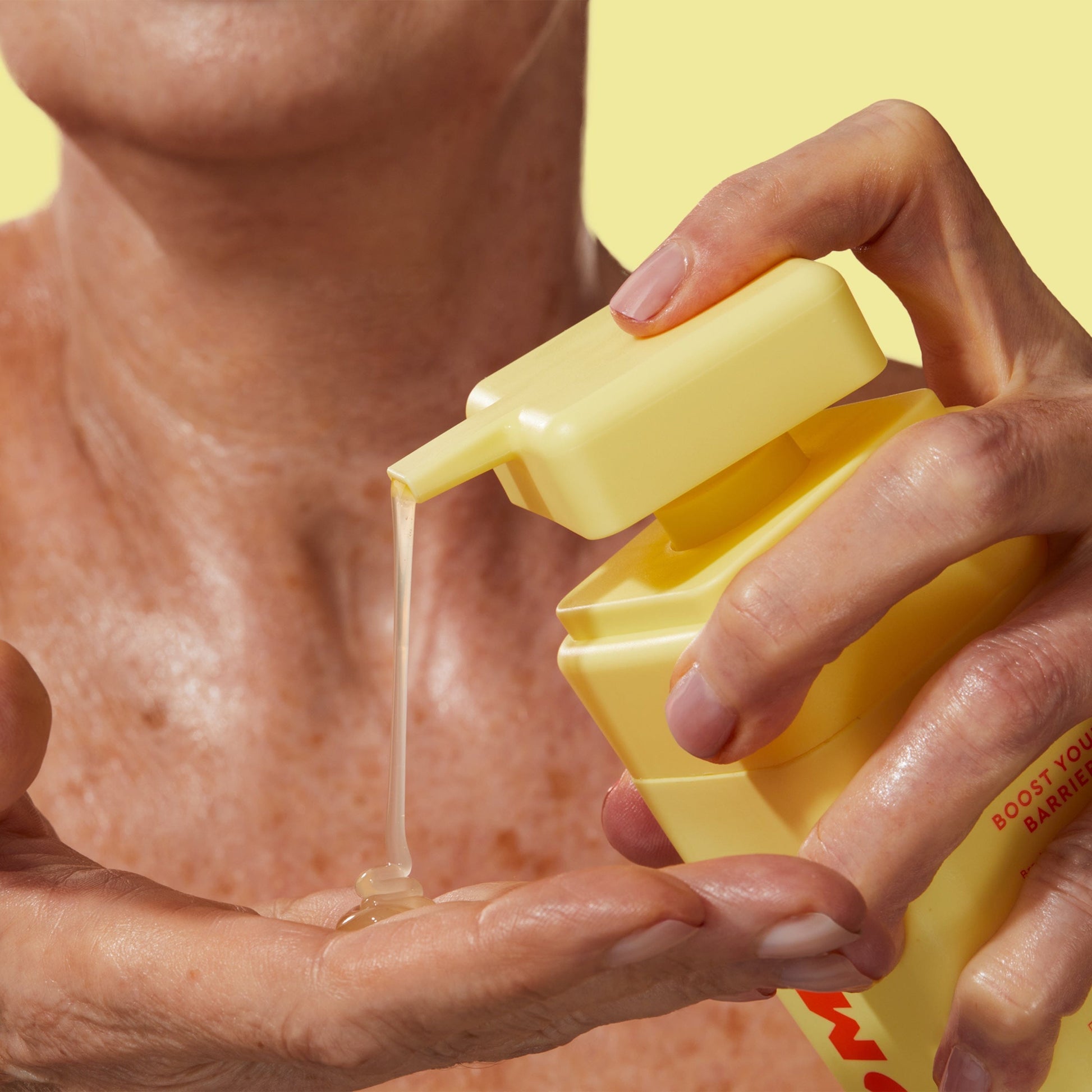 An older lady pressing a yellow bottle in one hand and collecting the product in the other.