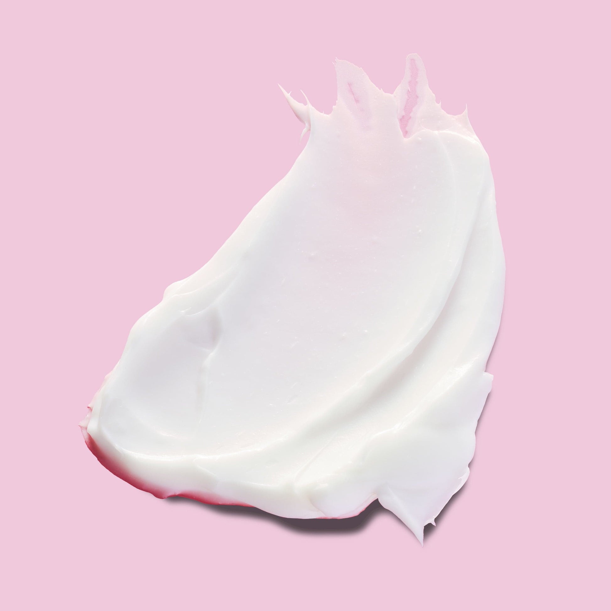 Thick white skincare product against a pink background.