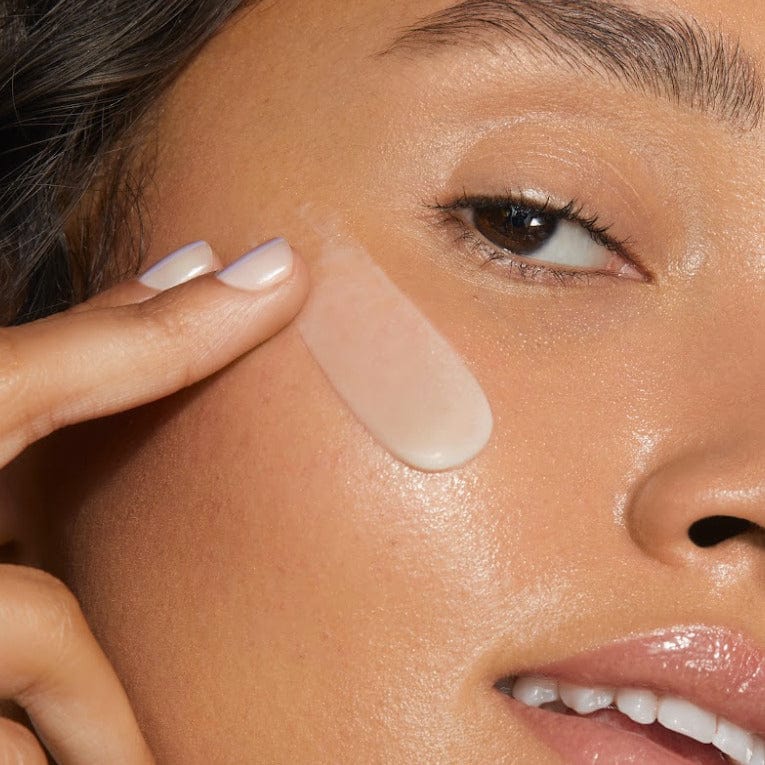 Closeup of a girl's face applying white skin cream with two fingers.