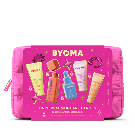 Bright pink rectangular pouch displaying BYOMA’s “Universal Skincare Heroes” set. Five skincare products are arranged on the pouch with a bold title and numbered steps. The design is accented with metallic pink and gold 3D icons like stars and planet rings.