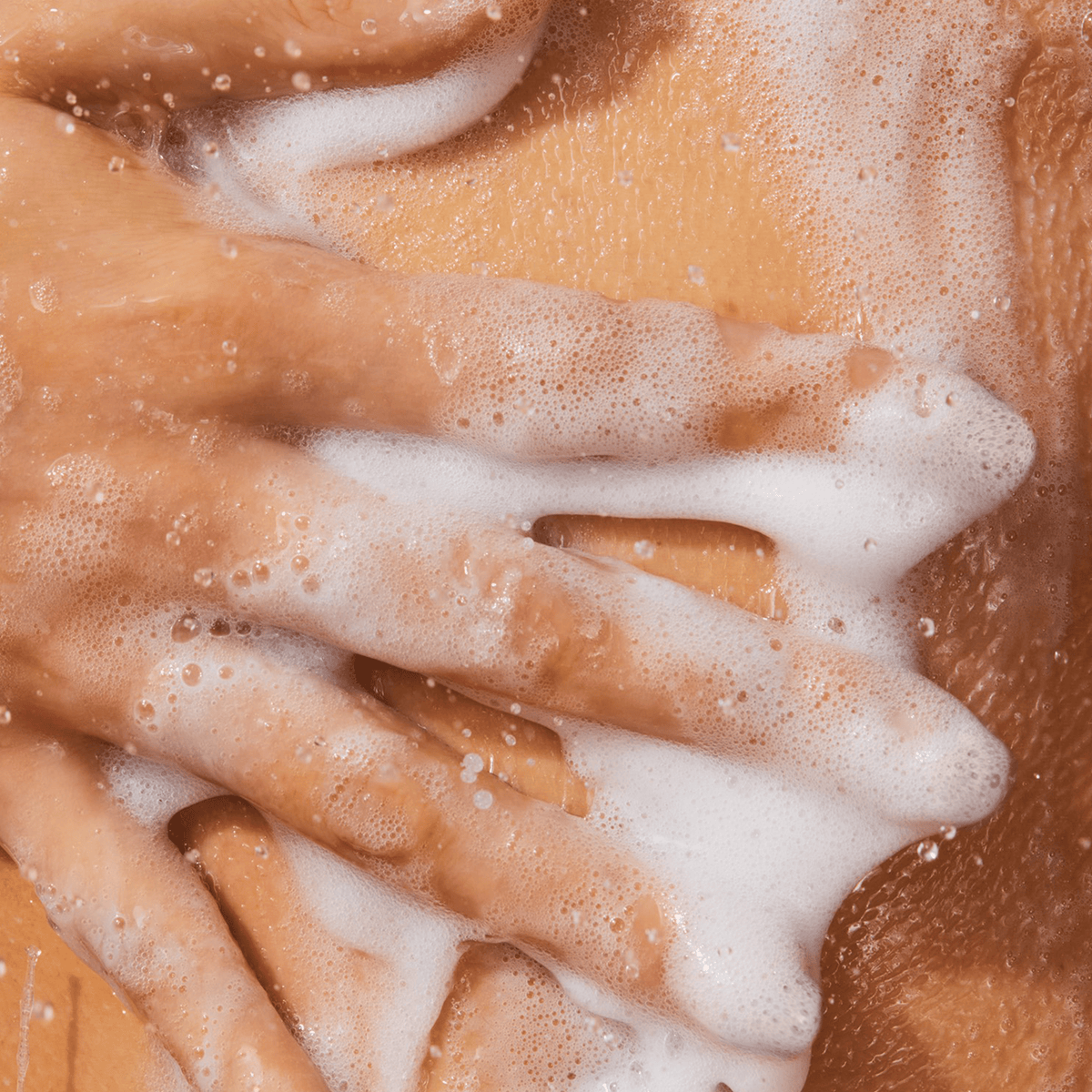 Five fingers with lather against a wet body.