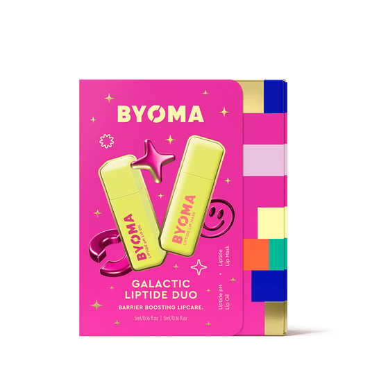 Bright pink rectangular packaging featuring two lime green tubes of BYOMA lip products crossed in an "X" shape. Decorative elements like a 3D star, a smiley face, and sparkles surround the products. Text reads: "BYOMA Galactic Liptide Duo. Barrier Boosting Lipcare." with product details: “Liptipe pH Lip Oil” and “Liptide Lip Mask”.