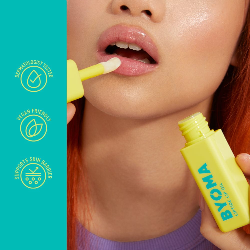 Person applying a yellow lip balm to their lips with product branding visible.